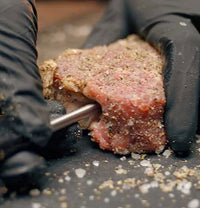 Meat thermometer being inserted into steak